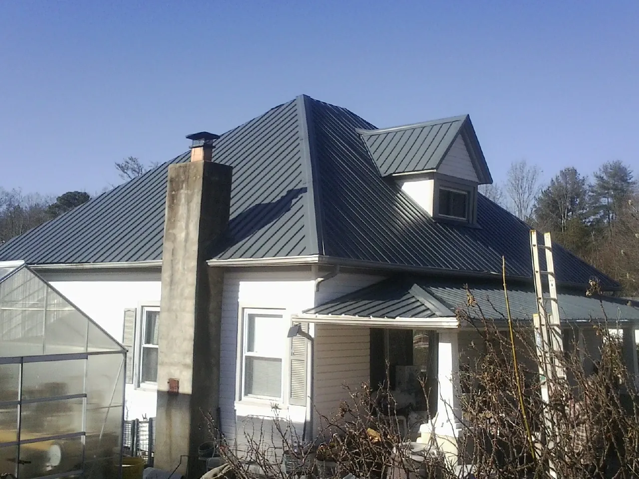Dark blue standing seam metal roof on a white farmhouse with dormer — Slate & Tile Roof Repair by Roofing Brothers in Chemult