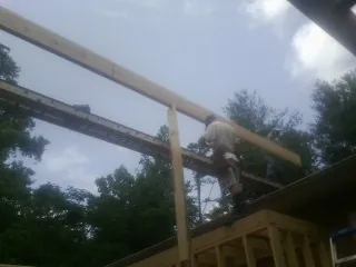Carpenter setting a ridge beam over a new addition frame — Ice Dam Removal by Roofing Brothers in Chemult