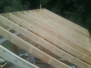 New roof rafters set over an addition before sheathing in Chemult