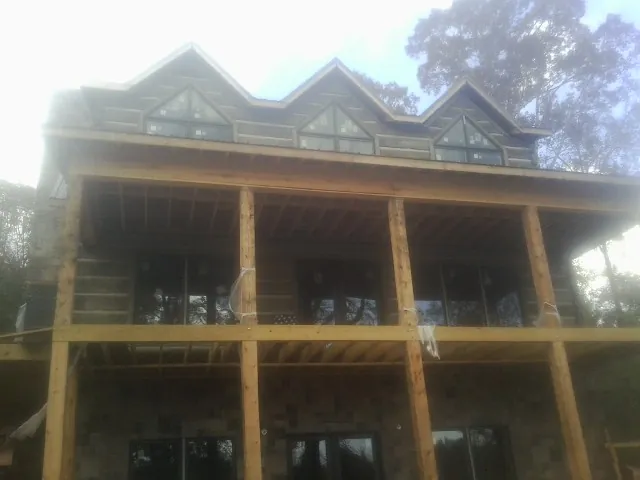 Dormers and porch framing on a large log home under construction — Roof Coating work by our crew in Chemult