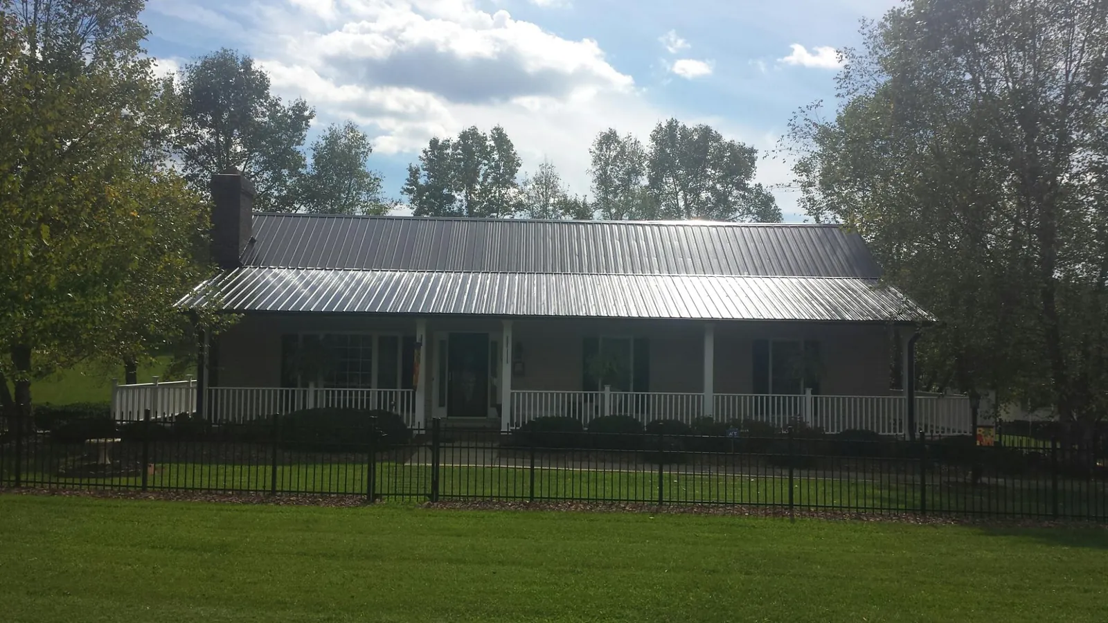 Gray metal roof on a brick ranch with a full width front porch — Gutter Guard Installation work by our crew in Chemult