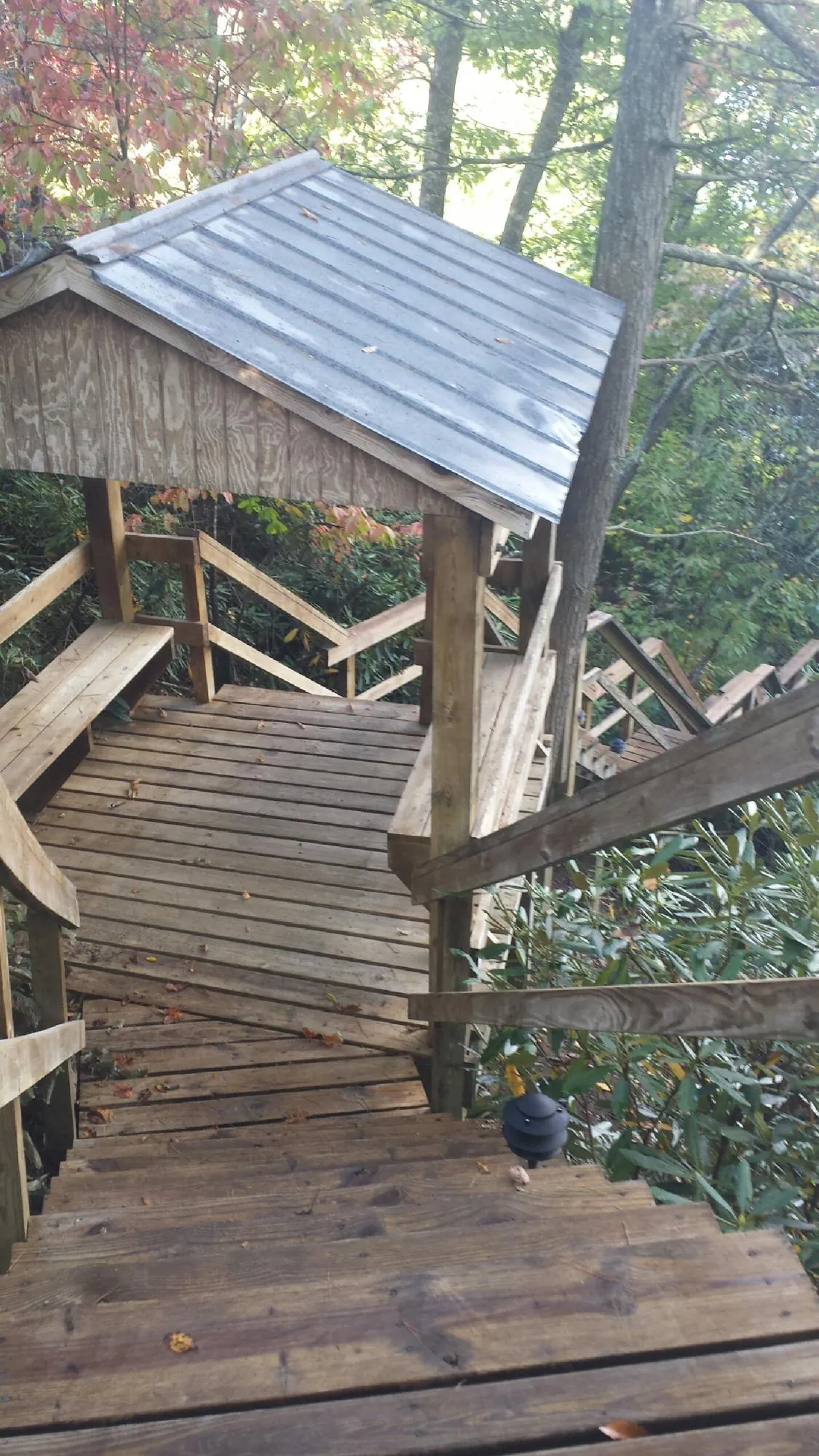 Metal roofed shelter over wooden steps on a wooded walkway — Skylight Repair & Installation work by our crew in Chemult