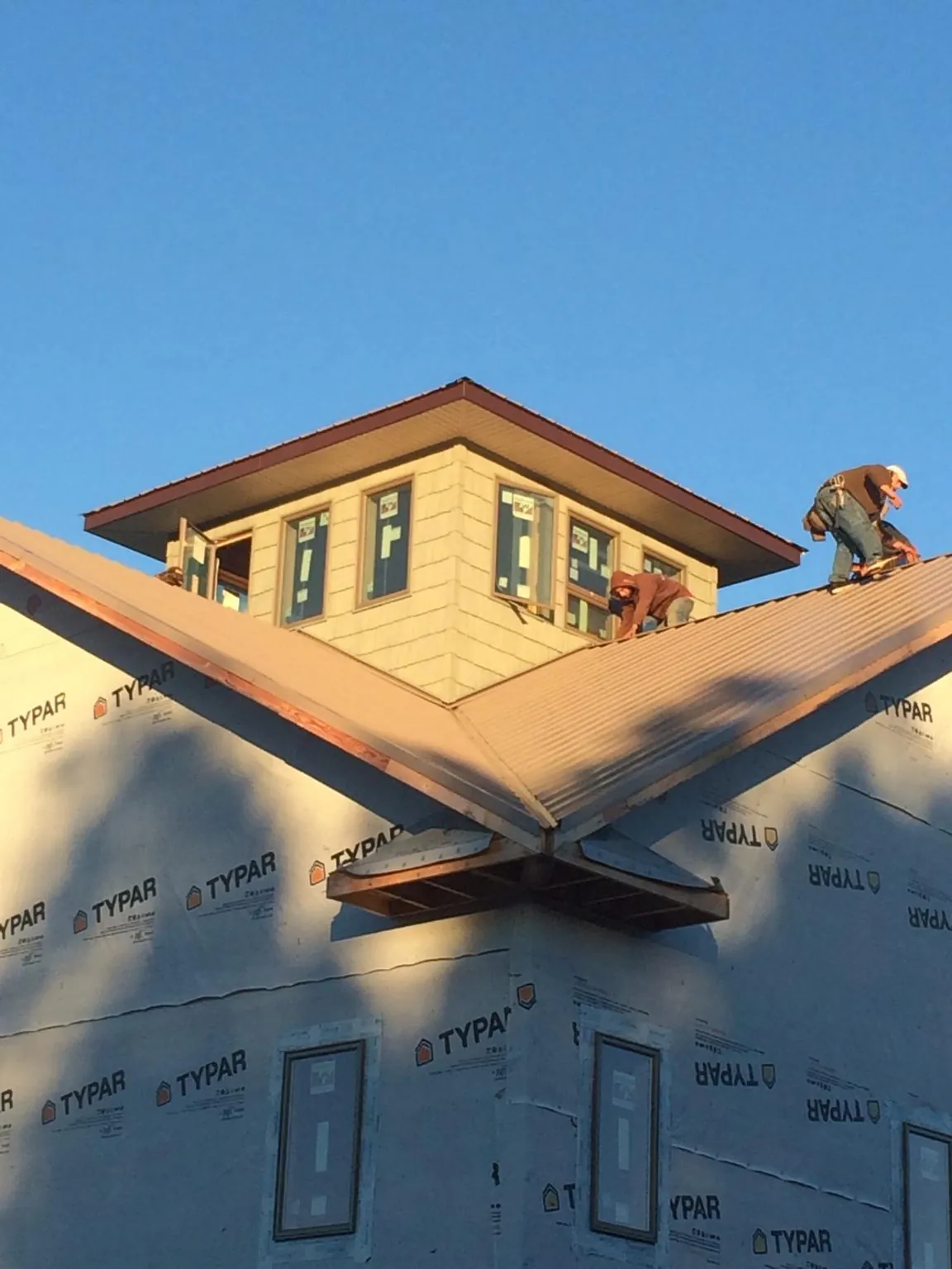 Roofers working around a rooftop cupola on a new metal roof at sunset — Roof Waterproofing in Chemult by Roofing Brothers